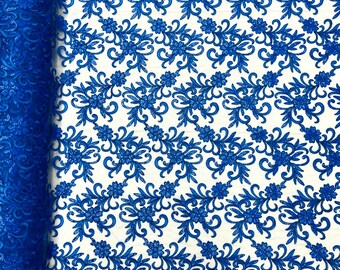 Puede incluir: Tela de encaje floral azul real con un acabado brillante. El encaje presenta un patrón repetitivo de delicadas flores y hojas.