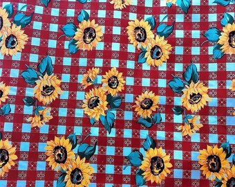 Peut inclure: Tissu à carreaux rouges et bleus avec un motif répétitif de tournesols jaunes. Les tournesols ont des feuilles vertes et sont disposés en grappes.
