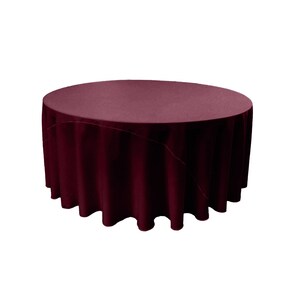 Peut inclure: Une nappe ronde de couleur bordeaux avec une surface lisse et sans plis. La nappe est drapé sur une table et a un léger drapé.