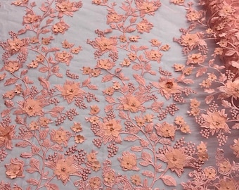 May include: Peach colored floral lace fabric with 3D flowers and beads. The fabric has a delicate, intricate design.