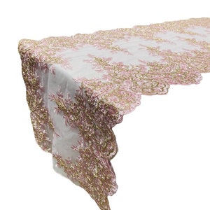 Op de afbeelding: Een witte kant tafelrunner met roze en gouden borduurwerk. De runner heeft een gegolfde rand en is perfect om een ​​toets van elegantie aan elke tafel te geven.