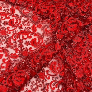 May include: Close-up of red lace fabric with an intricate floral pattern. The fabric is embellished with sequins, adding a subtle shimmer. The design features swirling vines and floral motifs, creating a luxurious and detailed texture. Ideal for special occasion apparel.