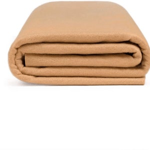 Puede incluir: Una tela de fieltro beige doblada. La tela es suave y lisa.