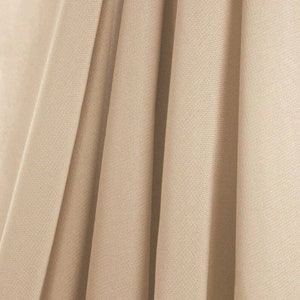 May include: Close-up of a beige fabric with vertical folds. The fabric has a subtle texture and a matte finish. The folds create shadows and highlights, adding depth to the image. The fabric appears to be a medium weight material, suitable for drapery or clothing.