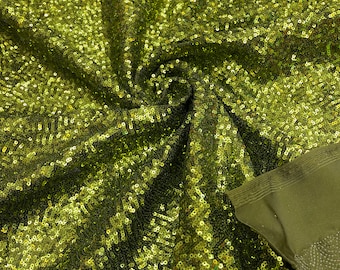 May include: Green sequined fabric with a subtle shimmer. The sequins are small and closely packed, creating a smooth, luxurious texture.