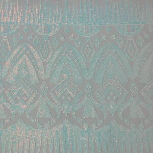 May include: Pale blue iridescent fabric with a geometric pattern. The fabric has a sequined texture and a scalloped edge.