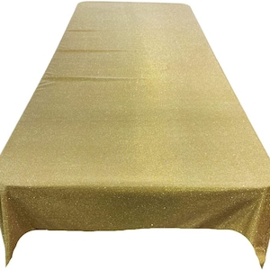 以下が含まれることがあります： 金色のグリッターのテーブルクロス。テーブルクロスは長方形で、滑らかで光沢のある表面をしています。