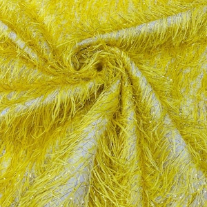 Puede incluir: Tela amarilla con una textura peluda y un brillo sutil. La tela está tejida con hilos finos que crean una apariencia peluda, casi como de piel.