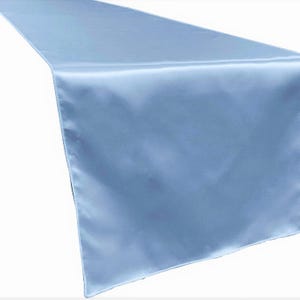May include: A light blue satin table runner. The runner is smooth and has a subtle sheen.
