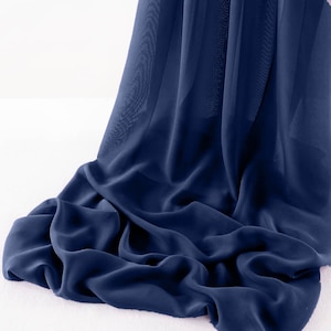 Puede incluir: Una tela azul oscuro con una textura suave y sedosa. La tela está drapeada y doblada, mostrando su naturaleza fluida.