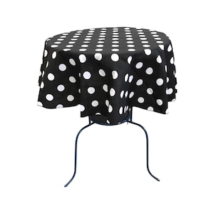 May include: A round table with a black tablecloth featuring a white polka dot pattern. The table has a dark blue metal frame with curved legs. The tablecloth drapes over the table, creating a classic, retro look.