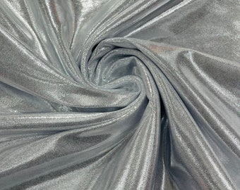 May include: Close-up of a silver fabric with a textured, reflective surface. The material is draped and folded, creating shadows and highlights. The fabric has a subtle, dotted pattern, adding depth and visual interest. Suitable for apparel and craft projects.