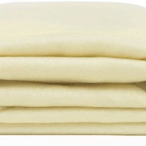 Puede incluir: Una manta de forro polar de color blanco roto doblada. La manta es suave y esponjosa, perfecta para mantenerse caliente en un día frío.