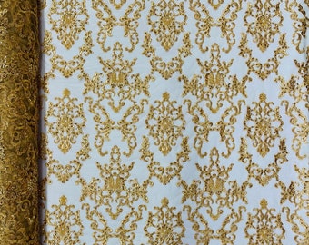 May include: Gold embroidered lace fabric with a damask pattern. The lace is on a white mesh background.