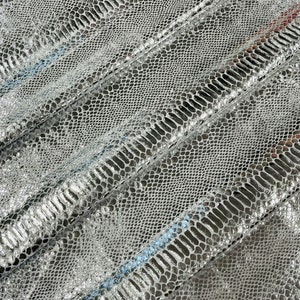 May include: Silver snakeskin fabric with a textured pattern. The fabric is folded in a few places, showing the texture of the material.