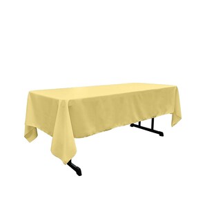 May include: A pale yellow rectangular tablecloth draped over a table. The tablecloth is made of a smooth, wrinkle-resistant fabric.