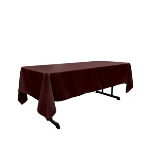 May include: A burgundy rectangular tablecloth draped over a table. The tablecloth is made of a smooth, wrinkle-resistant fabric.