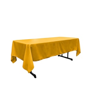 May include: A solid gold tablecloth draped over a table. The tablecloth is smooth and wrinkle-free.