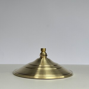 Puede incluir: Un cabezal de ducha de color dorado con un dise&ntilde;o redondo y plano y un &uacute;nico pico central.