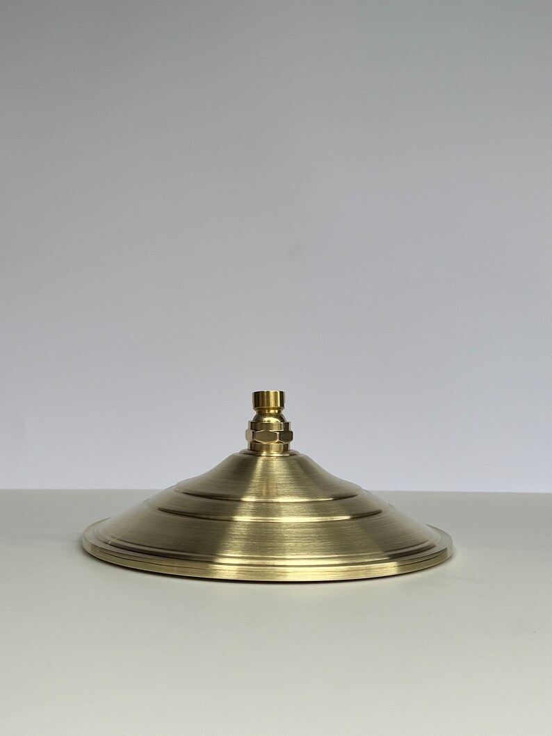 Puede incluir: Un cabezal de ducha de color dorado con un dise&ntilde;o redondo y plano y un &uacute;nico pico central.