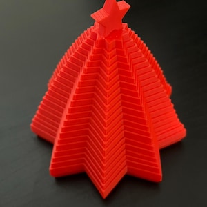 May include: A red 3D printed Christmas tree with a star on top. The tree is made of layers of stars that form a cone shape.