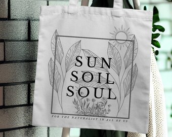 Peut inclure: Sac fourre-tout en toile blanche avec un dessin au trait noir de feuilles et d'un soleil. Le texte "SUN SOIL SOUL" est imprimé en noir sur le sac. Le texte "FOR THE NATURALIST IN ALL OF US" est imprimé en noir sous le logo.