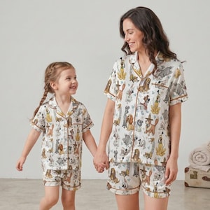 May include: A white ceramic mug with a black handle and the text "But First, Coffee" in a black, bold font. The mug is sitting on a white surface. The mug is approximately 4 inches tall.