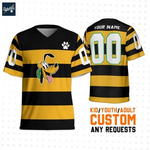 Puede incluir: Camiseta a rayas negras y amarillas con cuello en V y mangas cortas. La camiseta presenta un gráfico de dibujos animados de Pluto, una huella de pata y el número "00". La parte posterior de la camiseta tiene el texto "YOUR NAME" encima del número.