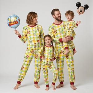Puede incluir: Una familia con pijamas a juego de Toy Story amarillos y verdes. Los pijamas tienen un estampado de cuadros con personajes de Toy Story. También se ve un globo de Toy Story y un globo de Mickey Mouse.