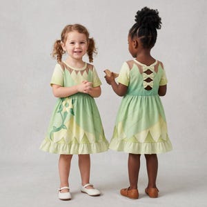 May include: A short-sleeved dress in shades of light green and yellow, featuring a petal-like hemline and a large floral graphic on the front. The back of the dress displays a cutout design with three horizontal bows along the upper back section.