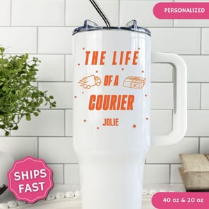 May include: A white stainless steel tumbler with a handle and a straw. The tumbler features orange text that reads THE LIFE OF A COURIER and JOLIE, accompanied by orange icons of a delivery truck and a package, surrounded by small orange stars.