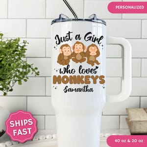 May include: A white stainless steel tumbler with a handle and a straw, featuring a graphic of three monkeys covering their eyes, ears, and mouth. The text reads Just a Girl who loves MONKEYS and the name Samantha in black and brown lettering.