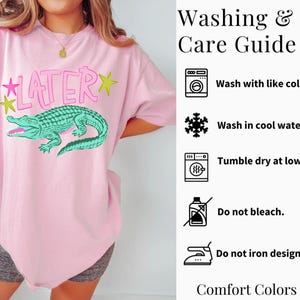 May include: Pink t-shirt with a green alligator graphic and the word "LATER" in pink. The shirt includes washing instructions and is made of Comfort Colors 1717 material.