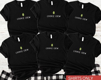 May include: Six black t-shirts with the text "COOKIE CREW" in white, each featuring a small green tree graphic. The shirts are displayed on a white and black checkered surface. The bottom right corner of the image has the text "SHIRTS ONLY".