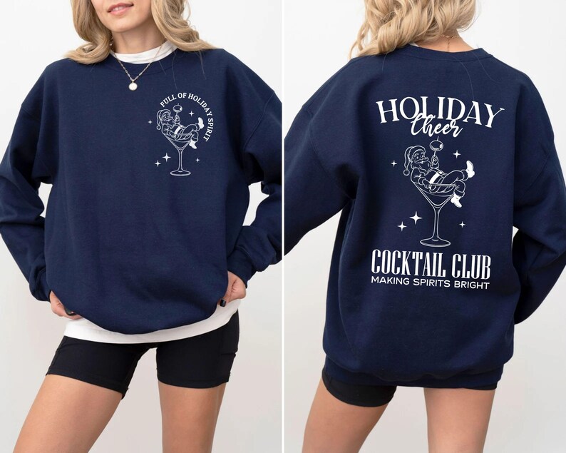 K&ouml;nnte beinhalten: Marineblaues Sweatshirt mit wei&szlig;er Grafik von Santa Claus in einem Cocktailglas. Auf der Vorderseite steht "FULL OF HOLIDAY SPIRIT". Auf der R&uuml;ckseite steht "HOLIDAY CHEER COCKTAIL CLUB MAKING SPIRITS BRIGHT."