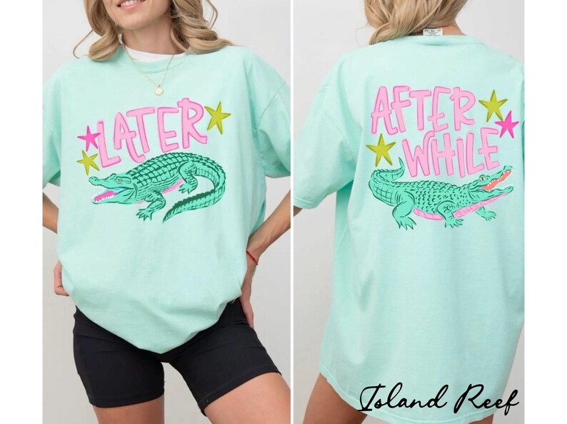 May include: Mint green t-shirt with a pink and green alligator graphic. The front of the shirt says "LATER" with a pink star and yellow star. The back says "AFTER WHILE" with a pink star and yellow star.