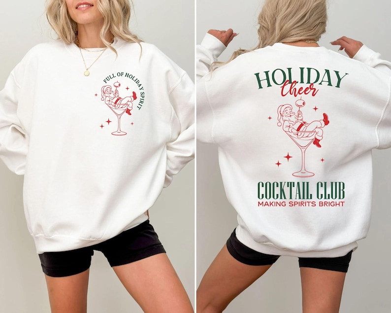 K&ouml;nnte beinhalten: Wei&szlig;es Sweatshirt mit einem roten und gr&uuml;nen Motiv von Santa Claus in einem Martini-Glas. Auf der Vorderseite steht "FULL OF HOLIDAY SPIRIT". Auf der R&uuml;ckseite steht "HOLIDAY CHEER COCKTAIL CLUB MAKING SPIRITS BRIGHT".