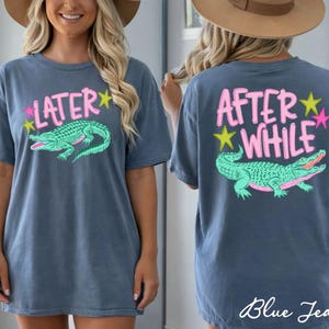 May include: Blue jean-colored t-shirt with a front and back design. The front says "LATER" in pink with a green alligator graphic. The back says "AFTER WHILE" in pink with a green alligator graphic. Pink and yellow stars are also included.