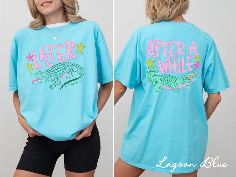 May include: Lagoon blue t-shirt with a front graphic of a green alligator and the word "LATER" in pink. The back of the shirt features the words "AFTER A WHILE" and a matching alligator graphic. The shirt has a relaxed fit.