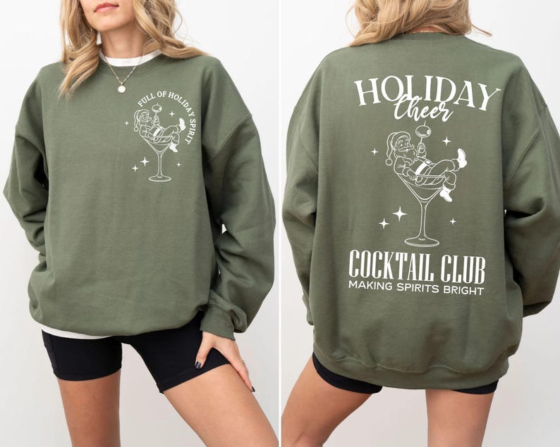 K&ouml;nnte beinhalten: Olivgr&uuml;nes Sweatshirt mit wei&szlig;er Grafik von Santa Claus in einem Martini-Glas. Auf der Vorderseite steht "FULL OF HOLIDAY SPIRIT". Auf der R&uuml;ckseite steht "HOLIDAY CHEER COCKTAIL CLUB MAKING SPIRITS BRIGHT".