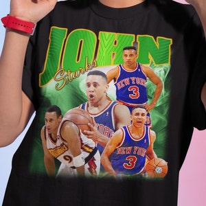 May include: Black t-shirt with a green and yellow graphic of basketball player John Starks. The graphic features a collage of Starks in different basketball uniforms, including a New York Knicks uniform.
