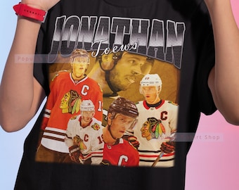 Pode incluir: Camiseta preta com um gráfico de estilo vintage do jogador de hóquei Jonathan Toews. O gráfico apresenta várias imagens de Toews com seu uniforme dos Chicago Blackhawks.