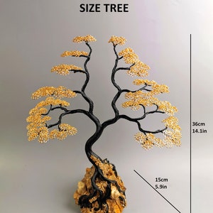 May include: A wire tree sculpture with a black trunk and branches, and golden leaves. The tree is mounted on a rock base. The sculpture is 14.1 inches tall, 12.6 inches wide, and 5.9 inches deep. The text "SIZE TREE" is above the tree.