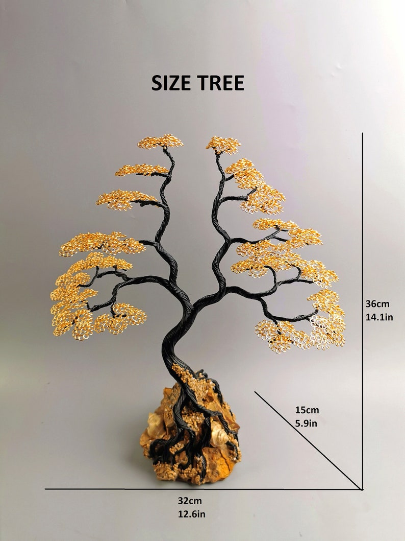 May include: A wire tree sculpture with a black trunk and branches, and golden leaves. The tree is mounted on a rock base. The sculpture is 14.1 inches tall, 12.6 inches wide, and 5.9 inches deep. The text "SIZE TREE" is above the tree.