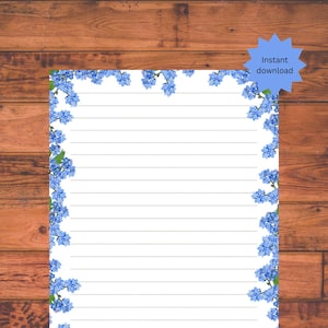 May include: Printable lined paper with a border of blue forget-me-not flowers. The paper is white with light gray lines. The text "Instant download" and "Unlimited printing" is on the image.