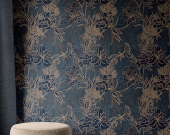 Op de afbeelding: Donkerblauw bloemenbehang met goudkleurige contouren van bloemen en bladeren. Het behang heeft een textuur en wordt gedeeltelijk bedekt door een donkerblauw gordijn. Een beige poef staat op de voorgrond.