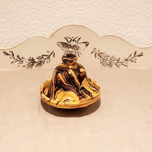 Könnte beinhalten: Eine kleine, gelbe und schwarze Keramik-Butterdose mit Deckel. Die Dose hat ein Wirbelmuster.