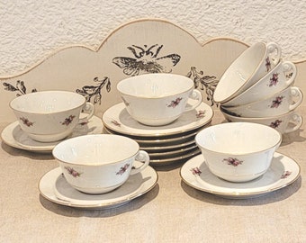 Service à thé en faïence fine. 8 tasses à thé et soucoupes assorties au décor fleuri et bords dorés.