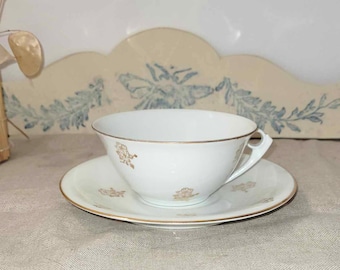 Delicate old chocolate cup in fine white earthenware with golden flower decoration Tea cup and matching saucer.