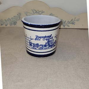 Könnte beinhalten: Ein weiß-blauer Keramikbehälter mit dem Text "Rumtopf Old English" und einer blauen Illustration eines Schlosses. Der Behälter hat einen blauen Rand und zwei blaue Streifen um den Boden.